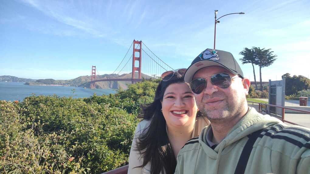 Joana y su pareja sonriendo con el puente Golden Gate de San Francisco al fondo durante su viaje por Estados Unidos.